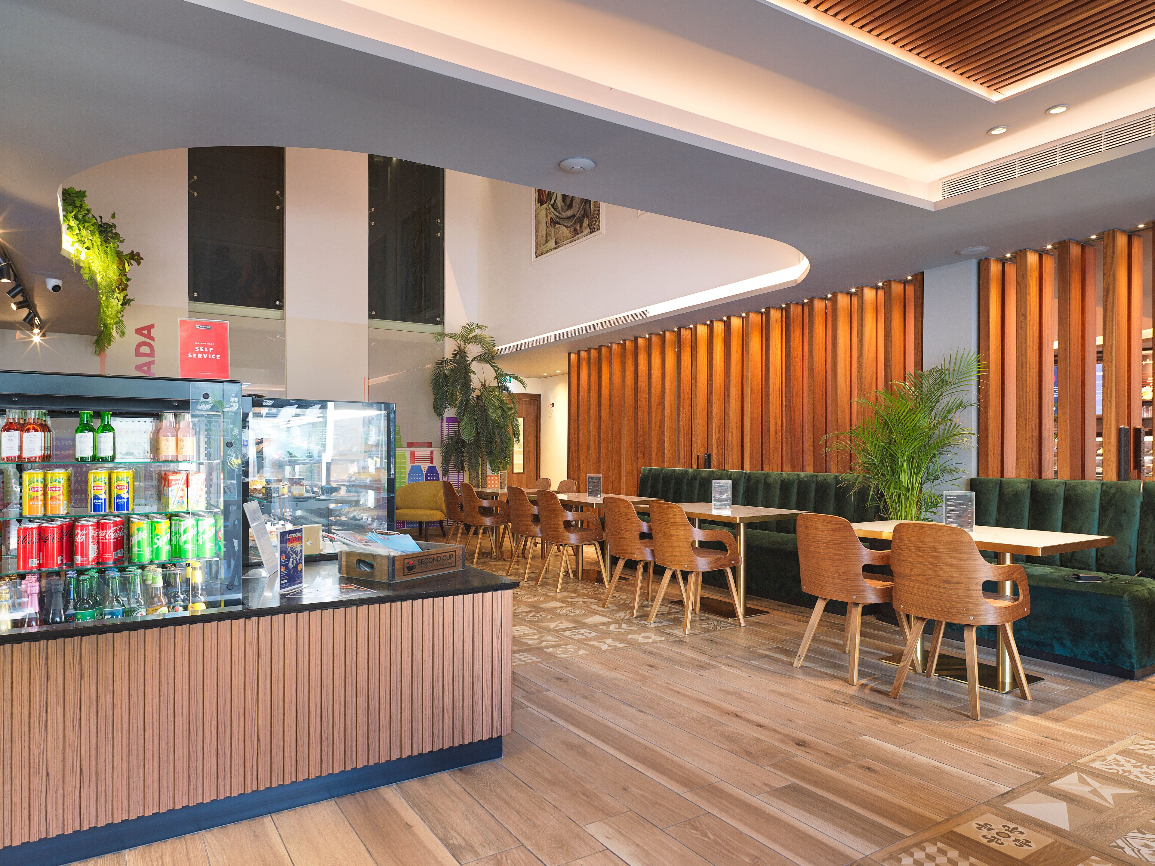 Un café moderno con mostrador de madera, zona de asientos y una pared decorativa.