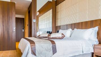 A modern hotel room with a large bed, wooden paneling, and a patterned headboard.