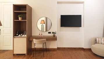 A modern living room with a wooden desk, a round mirror, a television mounted on the wall, and a sofa.
