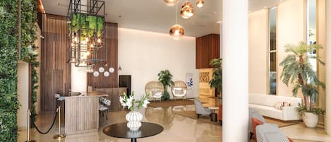 A modern lobby with a reception desk, seating area, and a large plant wall.