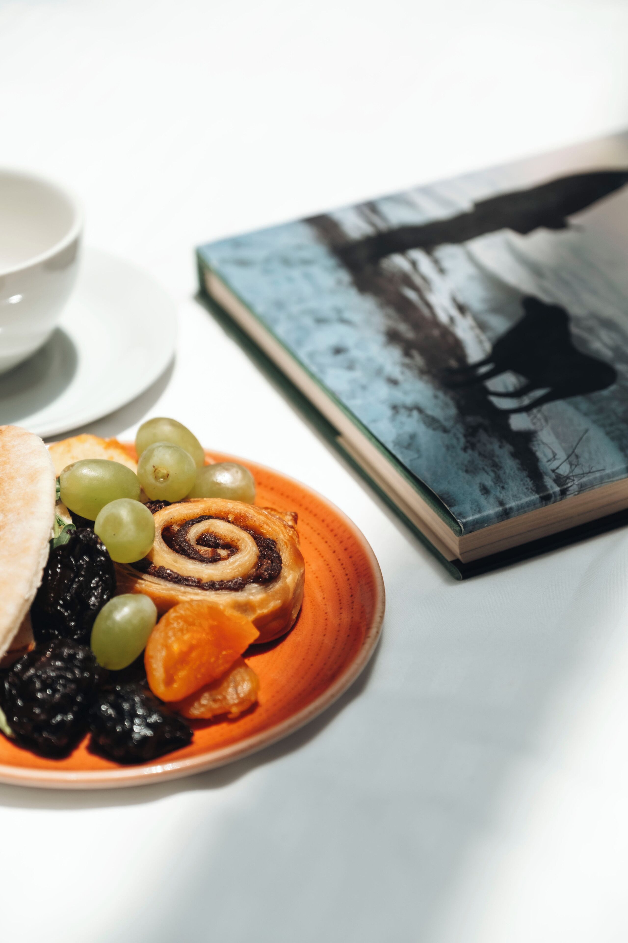 A plate of food with a book and a cup on a table.