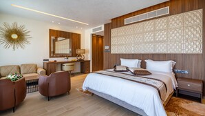 A modern hotel room with a large bed, a desk, a sofa, and a decorative wall panel. - Leonardo Boutique Hotel Larnaca (Larnaca)