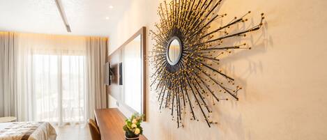 A modern hotel room with a large mirror, a wooden bench, and a potted plant.