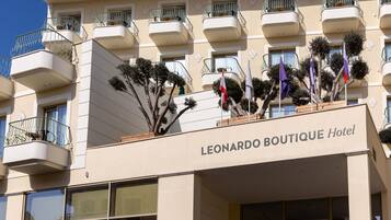 A hotel building with multiple balconies and a sign that reads "LEONARDO BOUTIQUE Hotel".