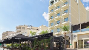 A multi-story hotel with balconies, outdoor seating areas, and a clear sky. - Leonardo Boutique Hotel Larnaca (Larnaca)