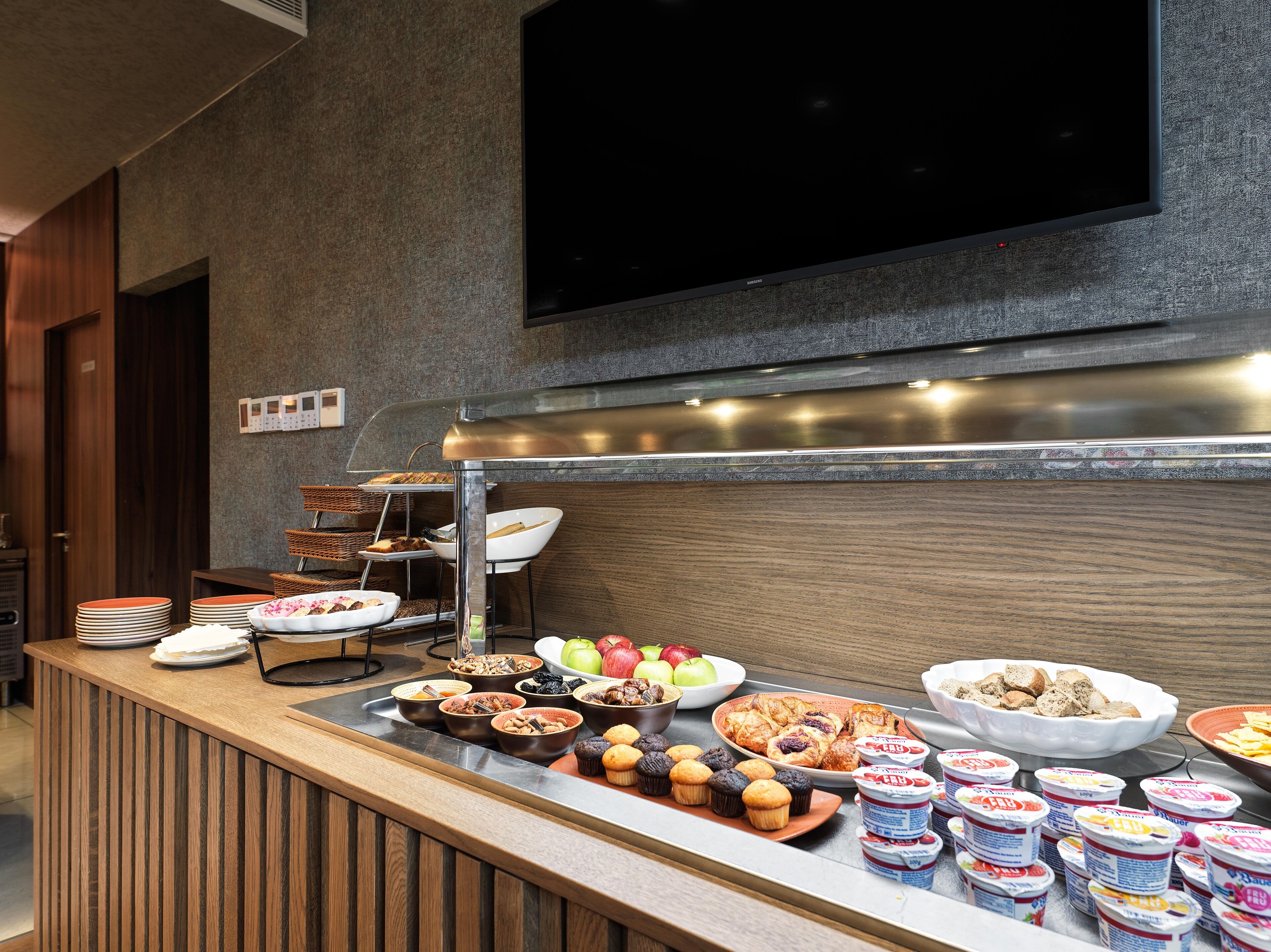 A buffet setup with various food items and a television mounted on the wall.