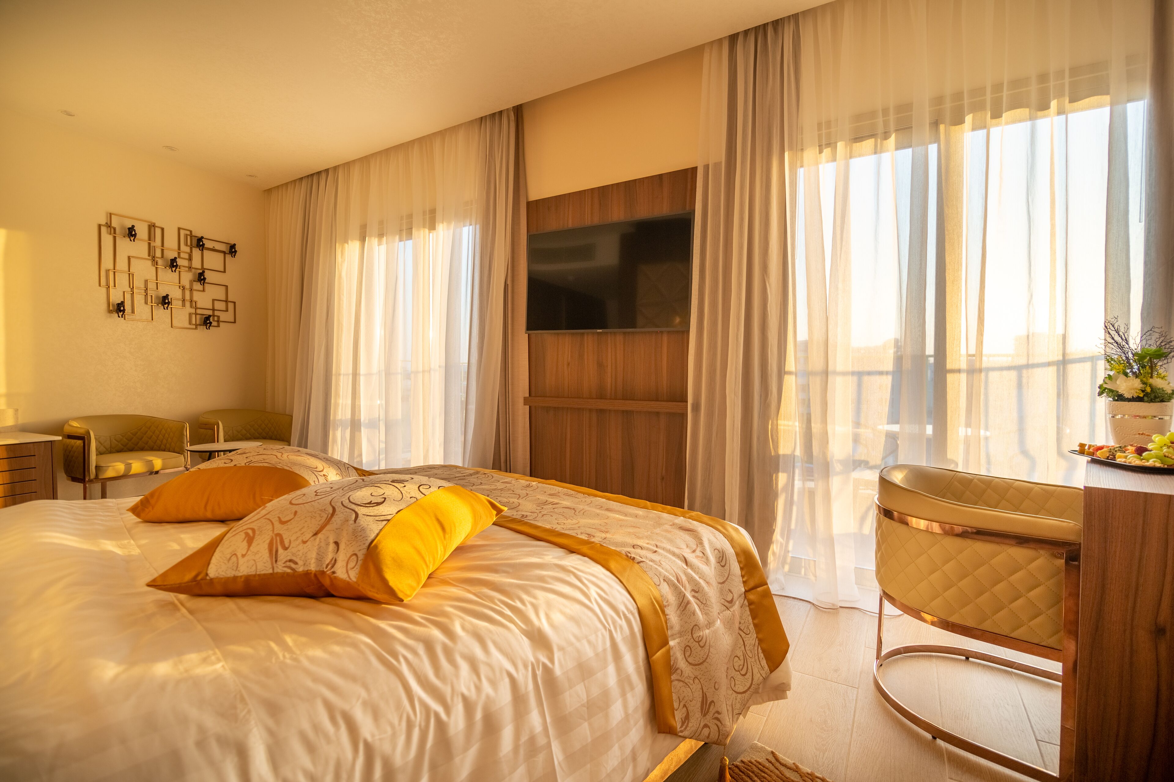 A hotel room with a large bed, a desk, and a TV mounted on the wall.