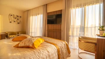 A hotel room with a large bed, a desk, and a TV mounted on the wall.