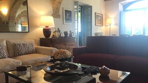 A living room with a glass coffee table, two sofas, a fireplace, and a view through an arched doorway.