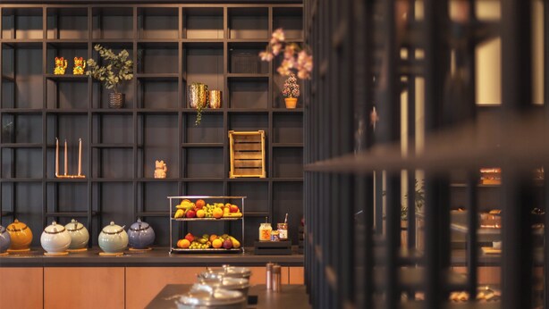 A modern kitchen with a black backsplash, wooden cabinets, and a fruit display. - Holiday Inn - the niu, Tab Dusseldorf Main Station by IHG (Düsseldorf)