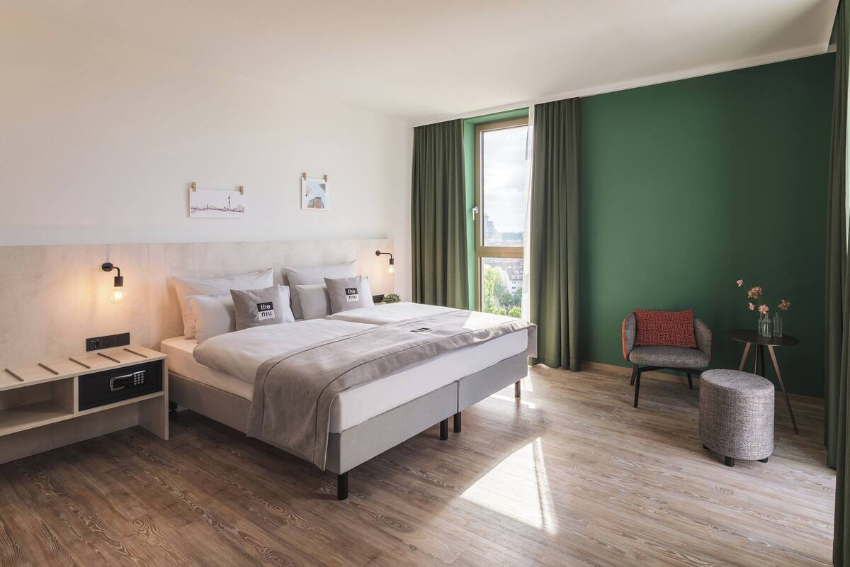 A modern bedroom with a large bed, bedside tables, a chair, and a small table with flowers.