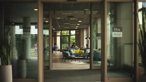 An entrance to a modern building with glass doors, a seating area with sofas and a coffee table, and a visible sign that reads "the niu". - Holiday Inn - the niu, Tab Dusseldorf Main Station by IHG (Düsseldorf)