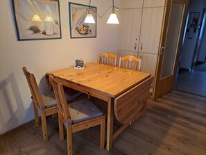 A wooden dining table with four chairs, two wall-mounted lamps, and a cabinet with a sliding door.