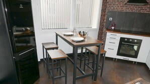 A compact kitchen with a refrigerator, a stove, and a dining area with stools. - Meublé de Tourisme 3 Loft Industriel à Fismes (Fismes)
