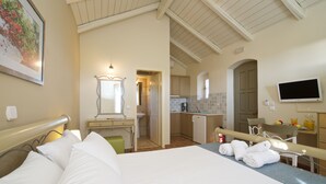 Habitación de hotel con cama, escritorio, silla, televisor y vista a la cocina.