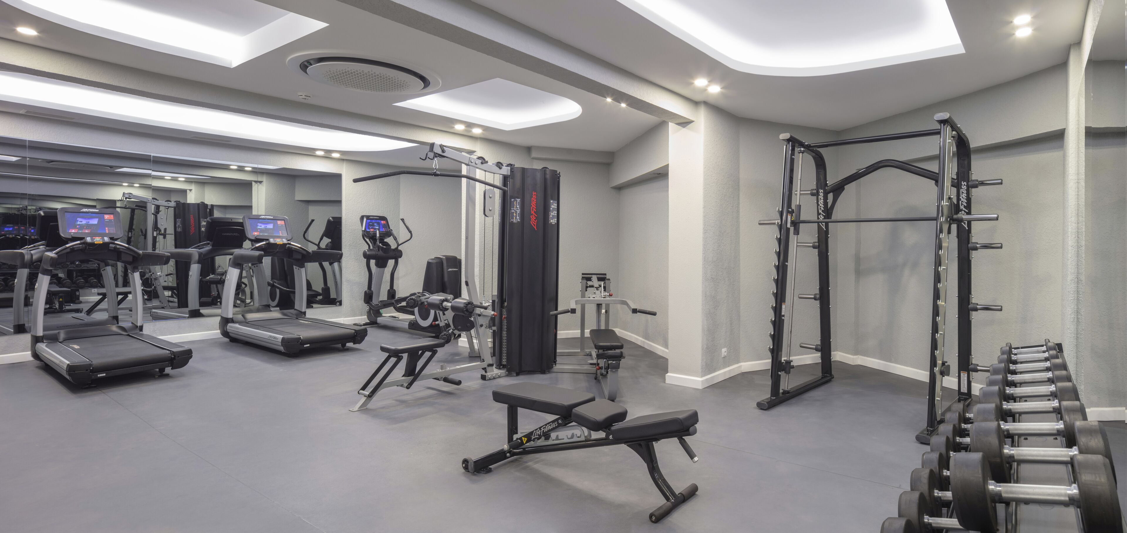 A modern gym with treadmills, weight machines, and free weights.