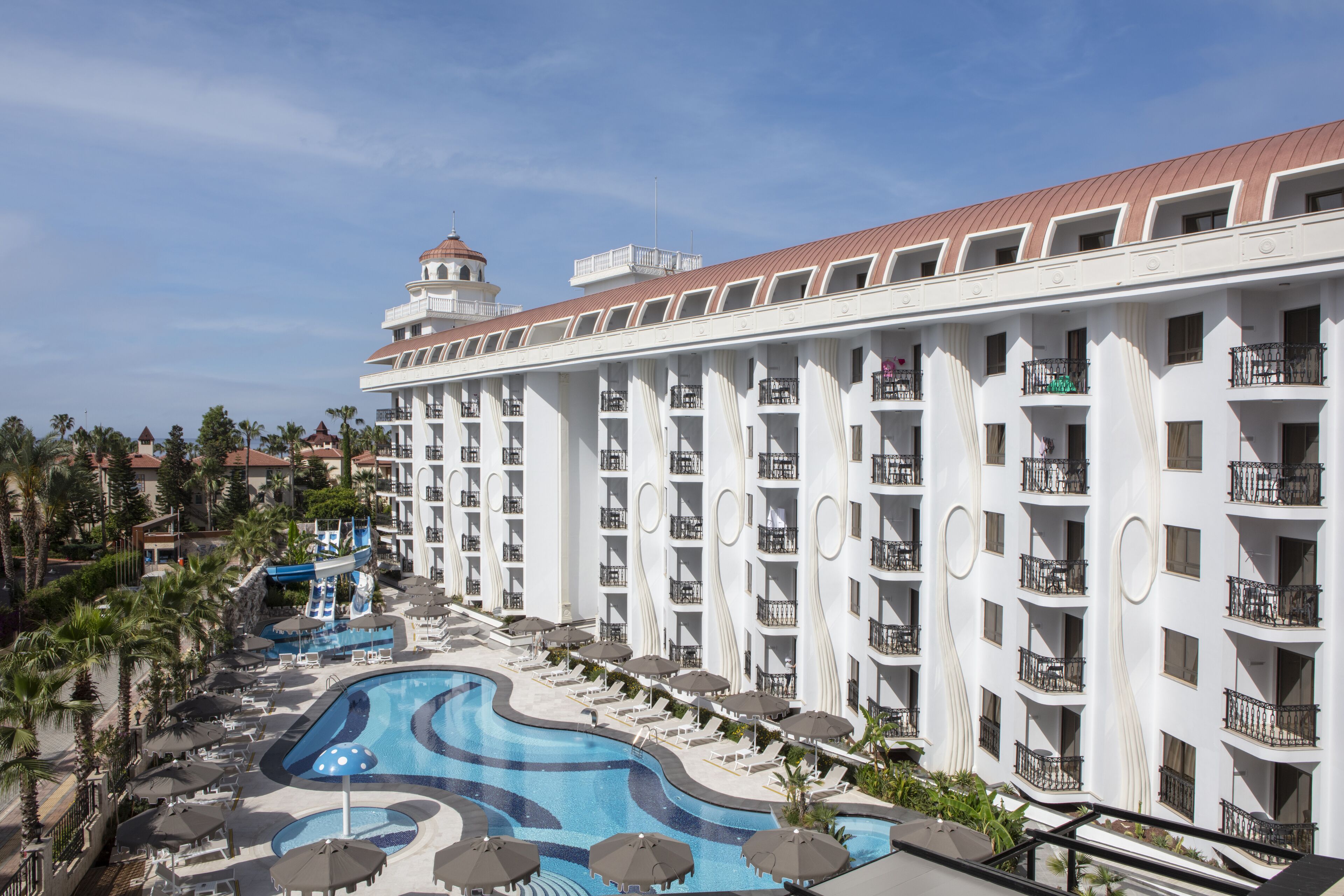 Un hotel con varios balcones, piscina y tobogán de agua.