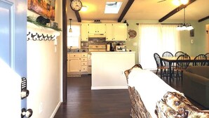 Una cocina con armarios de madera, una isla central y una zona de comedor con sillas.