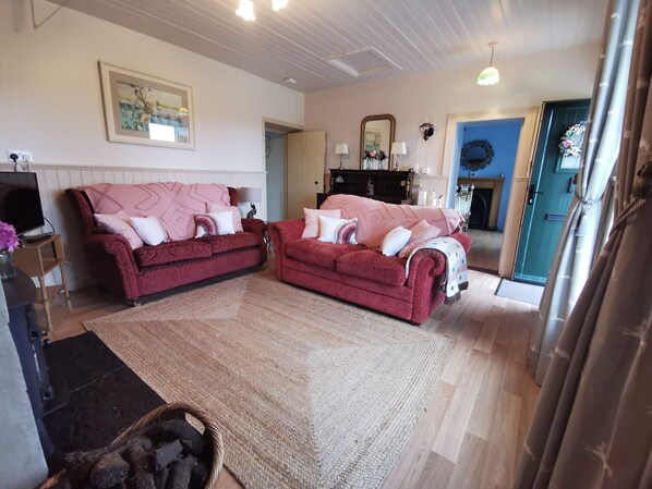 A living room with two red sofas, a large rug, and a television on a wooden stand. - 🌷🥀🌺New Listing 🌷🥀🌺 (Dunkineely)