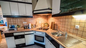 Eine moderne Küche mit weißen Schränken, einer Edelstahl-Spüle, einem Backofen und einem Gasherd.