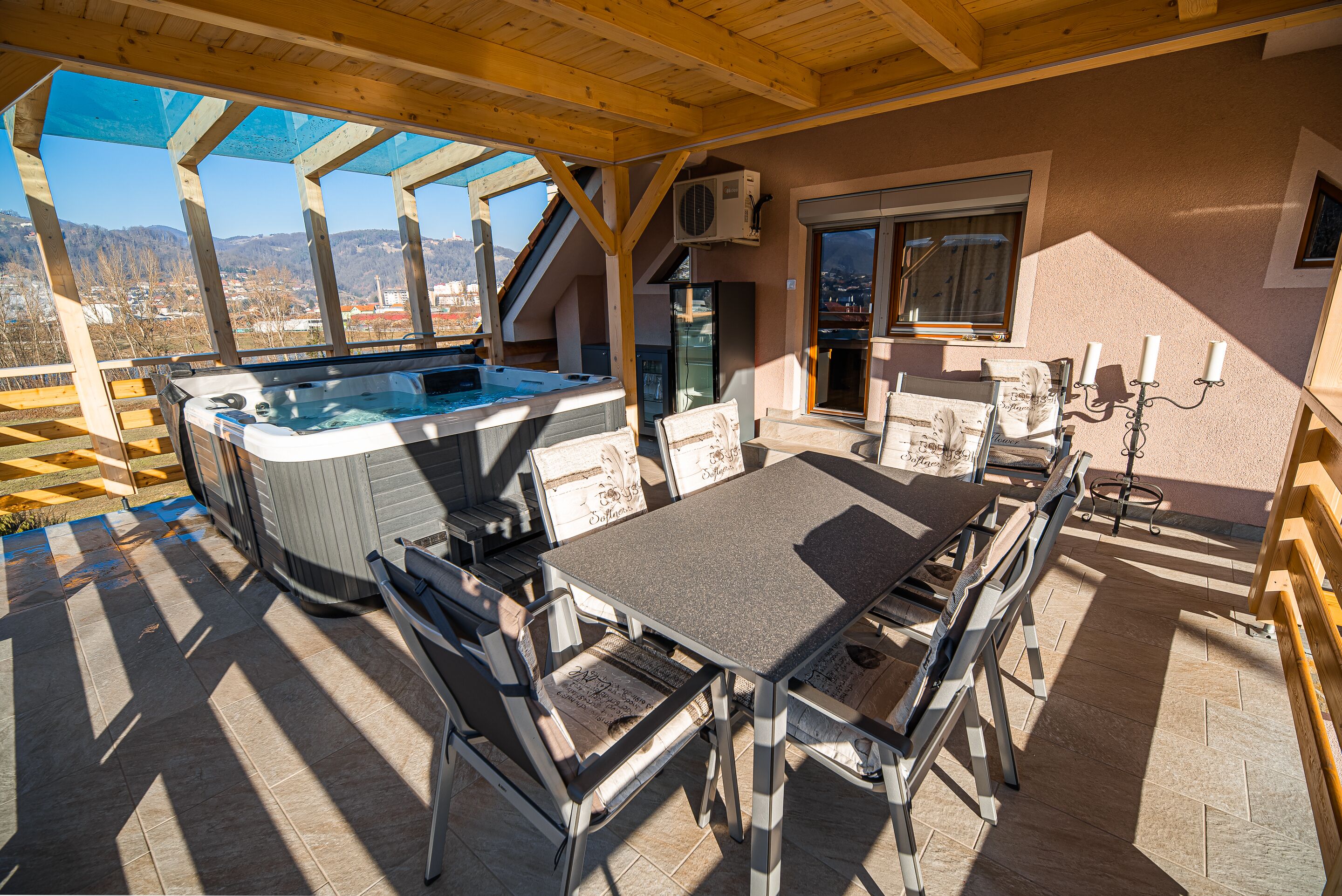 An outdoor patio with a hot tub, table, chairs, and a view of the mountains.