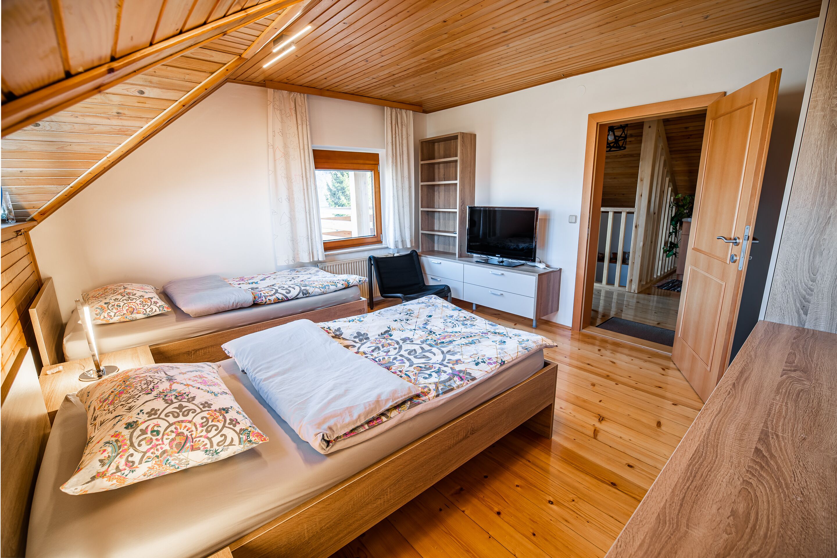 A bedroom with two beds, a desk, and a television.