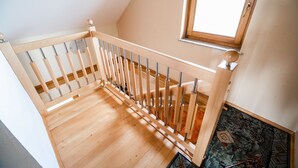 Eine Holztreppe mit Geländer, einem Fenster und einem gemusterten Boden.
