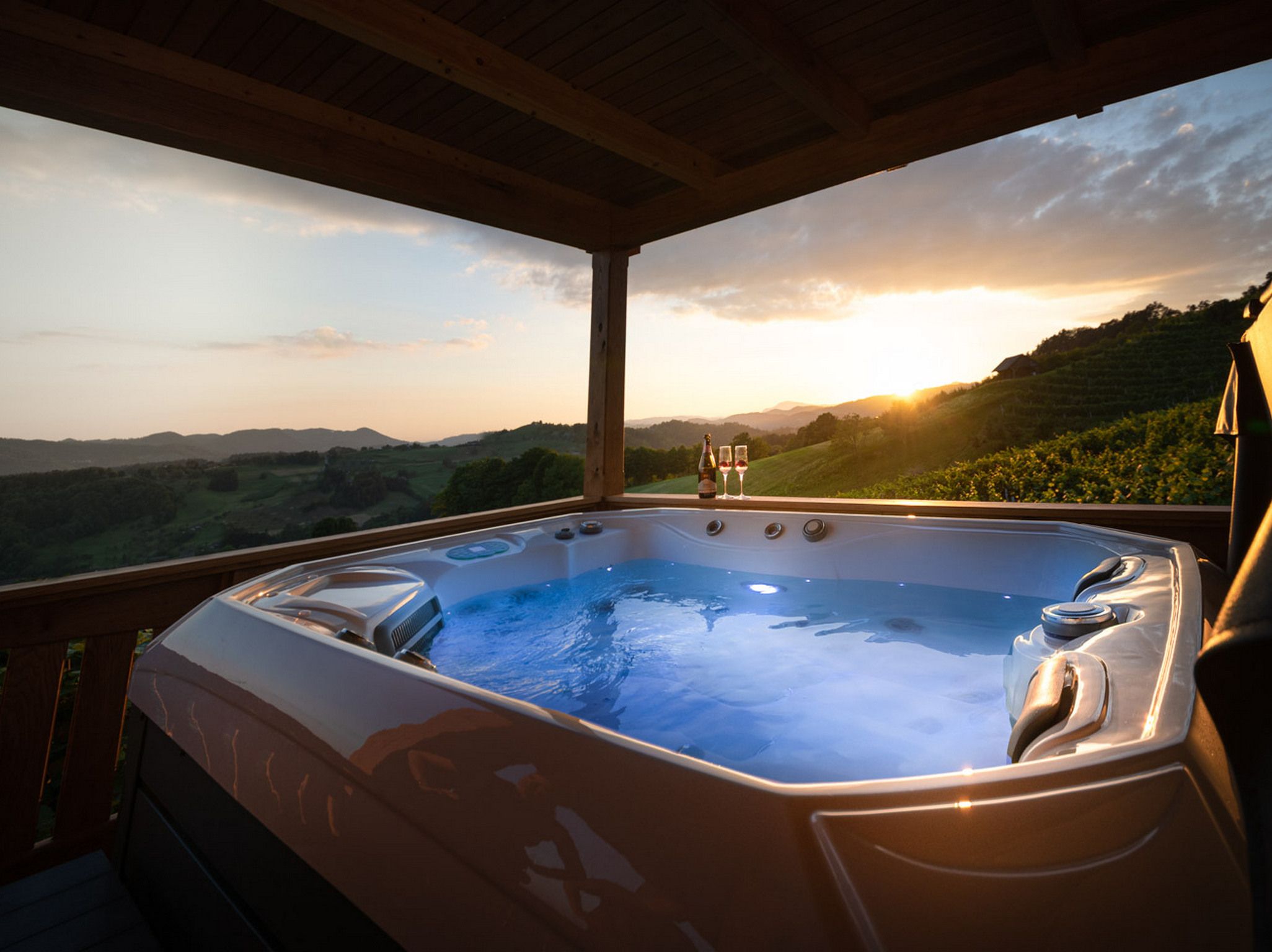 Un bain à remous avec vue sur un vignoble et les collines au coucher du soleil.