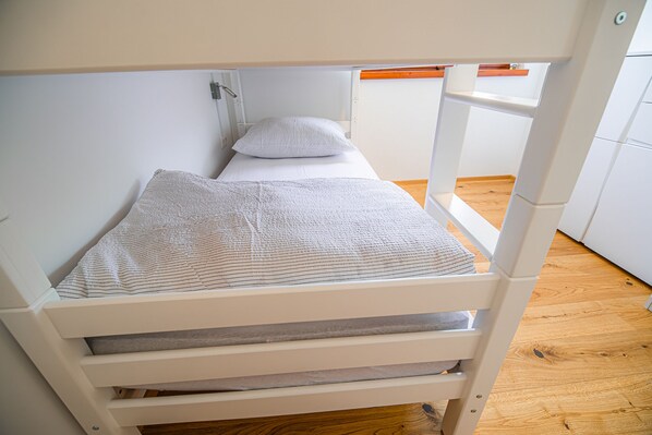 A bunk bed with a white frame and a wooden floor.