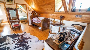 A cozy room with a wooden ceiling, a bed, a mirror, a small table with a clock, and a cowhide rug. - Authentic Countryside Villa With Hot tub (Krsko)