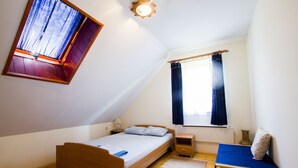 A small, well-lit bedroom with a sloped ceiling, a single bed, a bedside table, a nightstand, a window with curtains, and a skylight. - Holiday Home Juricko (Brezice)