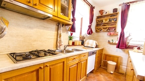 A kitchen with wooden cabinets, a gas stove, a sink, and a dishwasher. - Holiday Home Juricko (Brezice)