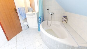 A bathroom with a bathtub, a sink, a toilet, and a shower. - Holiday Home Juricko (Brezice)