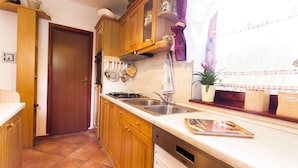 A kitchen with wooden cabinets, a double sink, and a stove. - Holiday Home Juricko (Brezice)