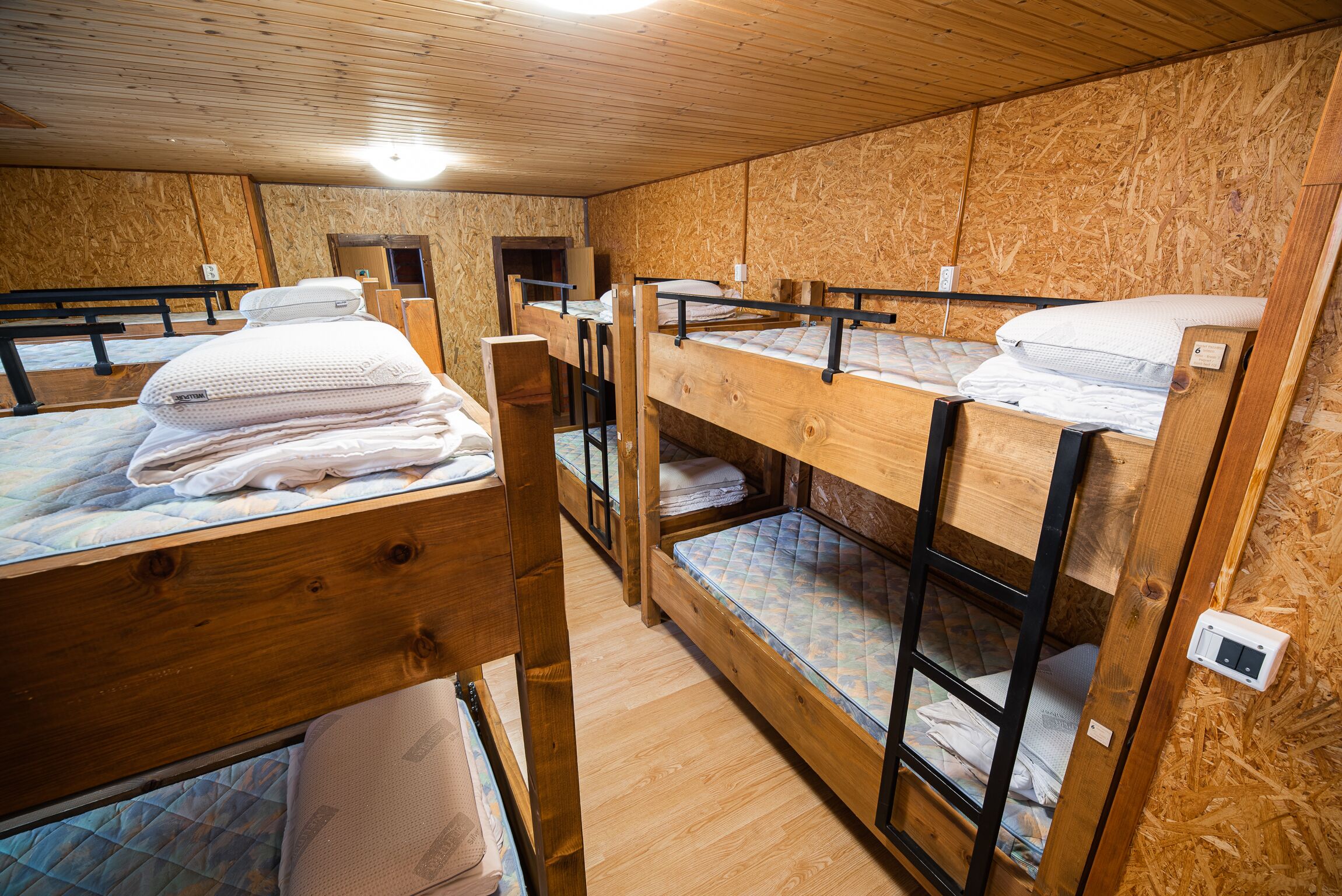 A room with bunk beds, wooden walls, and a simple layout.