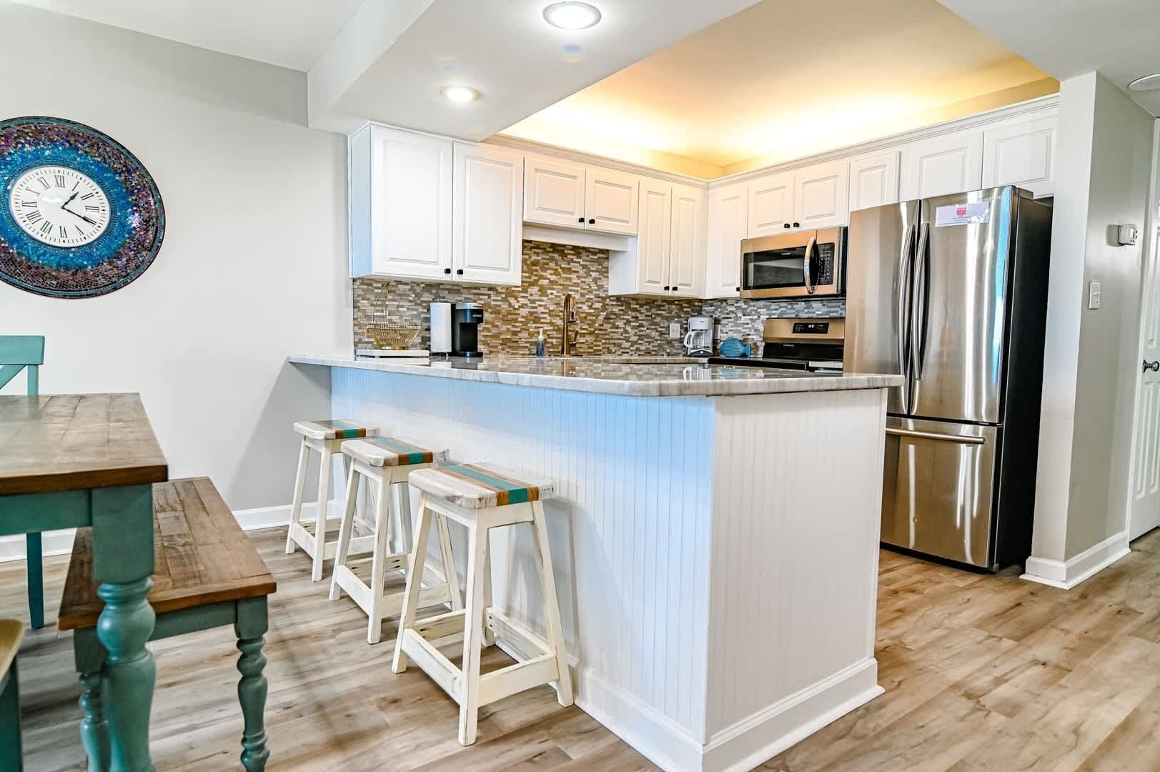 A modern kitchen with white cabinetry, a stainless steel refrigerator, a microwave, and a coffee maker.