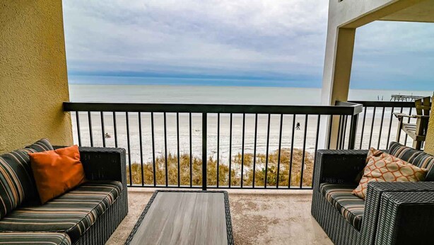 A balcony with wicker furniture, a view of the ocean, and a railing. - Direct Oceanfront Magic at Sea Marsh w Pool (North Myrtle Beach)