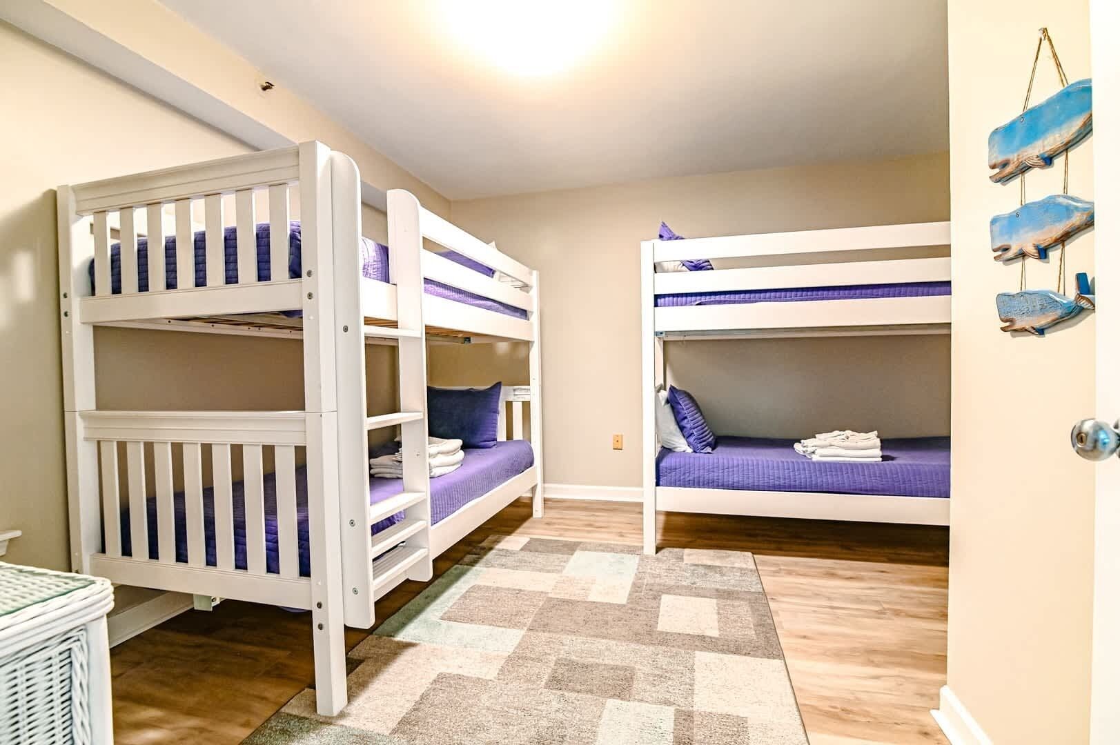 Ein Zimmer mit Etagenbetten, einem kleinen Tisch und einem Teppich.
