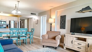 A living room with a sofa, a chair, a television, and a cabinet. - Direct Oceanfront Magic at Sea Marsh w Pool (North Myrtle Beach)
