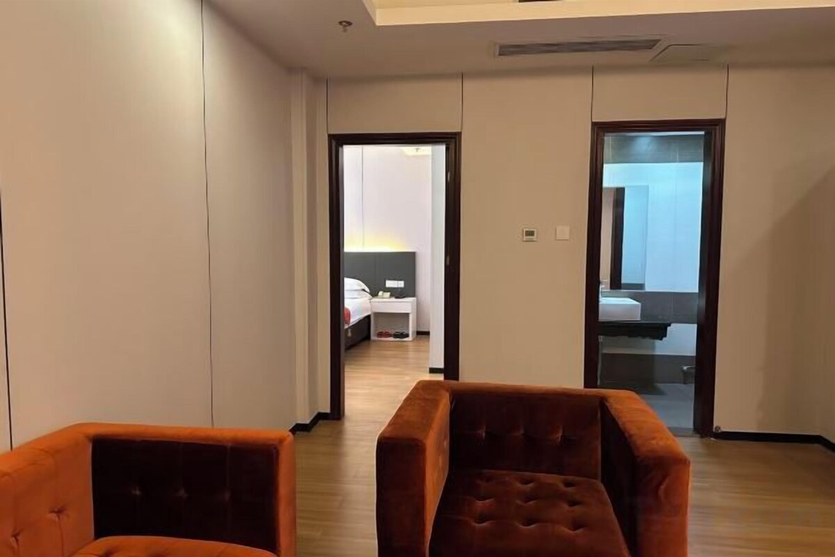 A hotel room with a bed, a bedside table, and a large window.