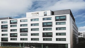 A modern hotel building with a flat facade, multiple windows, and a sign at the top. - Holiday Inn - the niu, Form Stuttgart Feuerbach by IHG (Stuttgart)