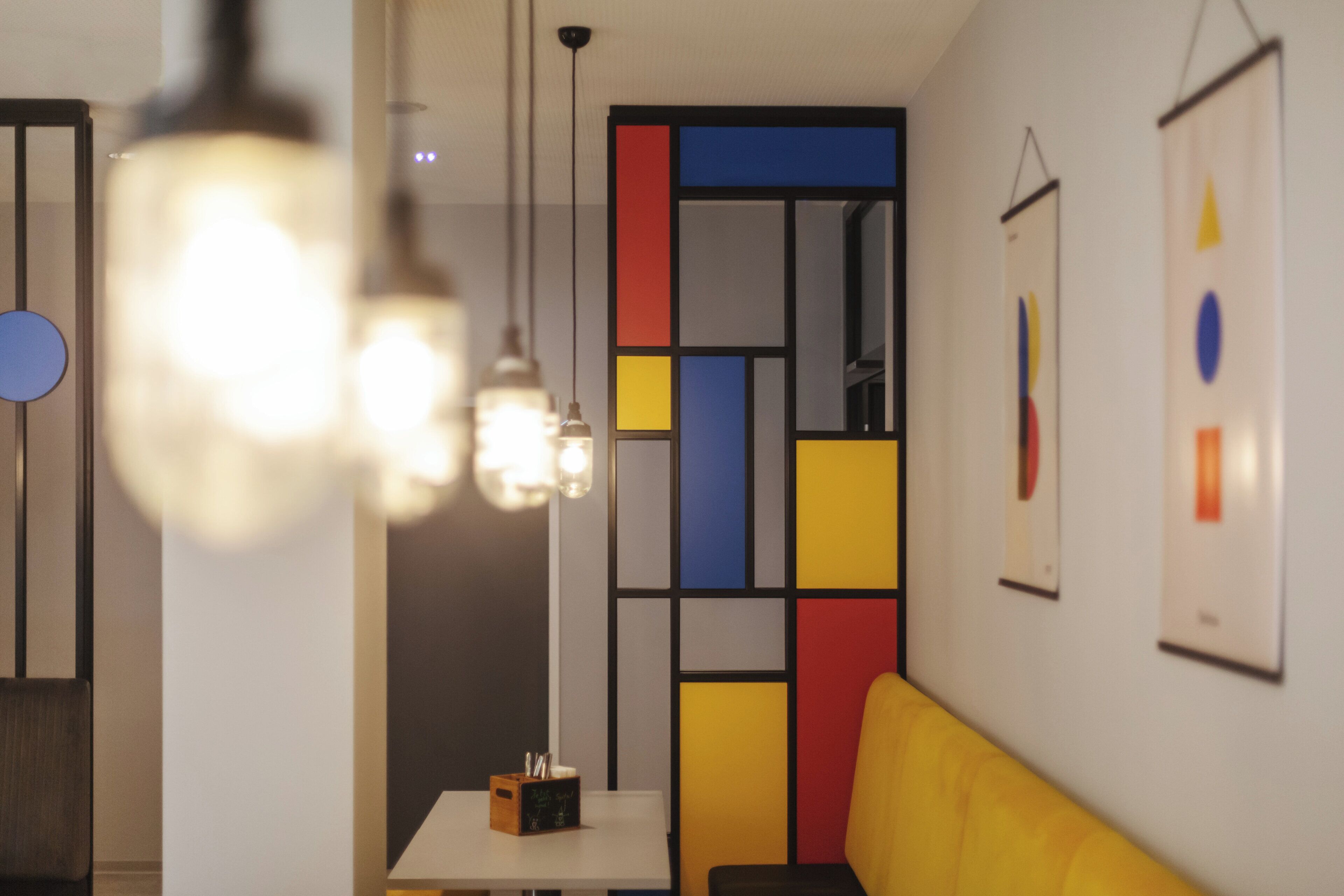 Ein modernes Interieur mit einem Tisch, Stühlen und einer farbenfrohen Raumtrennung.