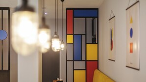 A modern interior with a table, chairs, and a colorful wall partition. - Holiday Inn - the niu, Form Stuttgart Feuerbach by IHG (Stuttgart)