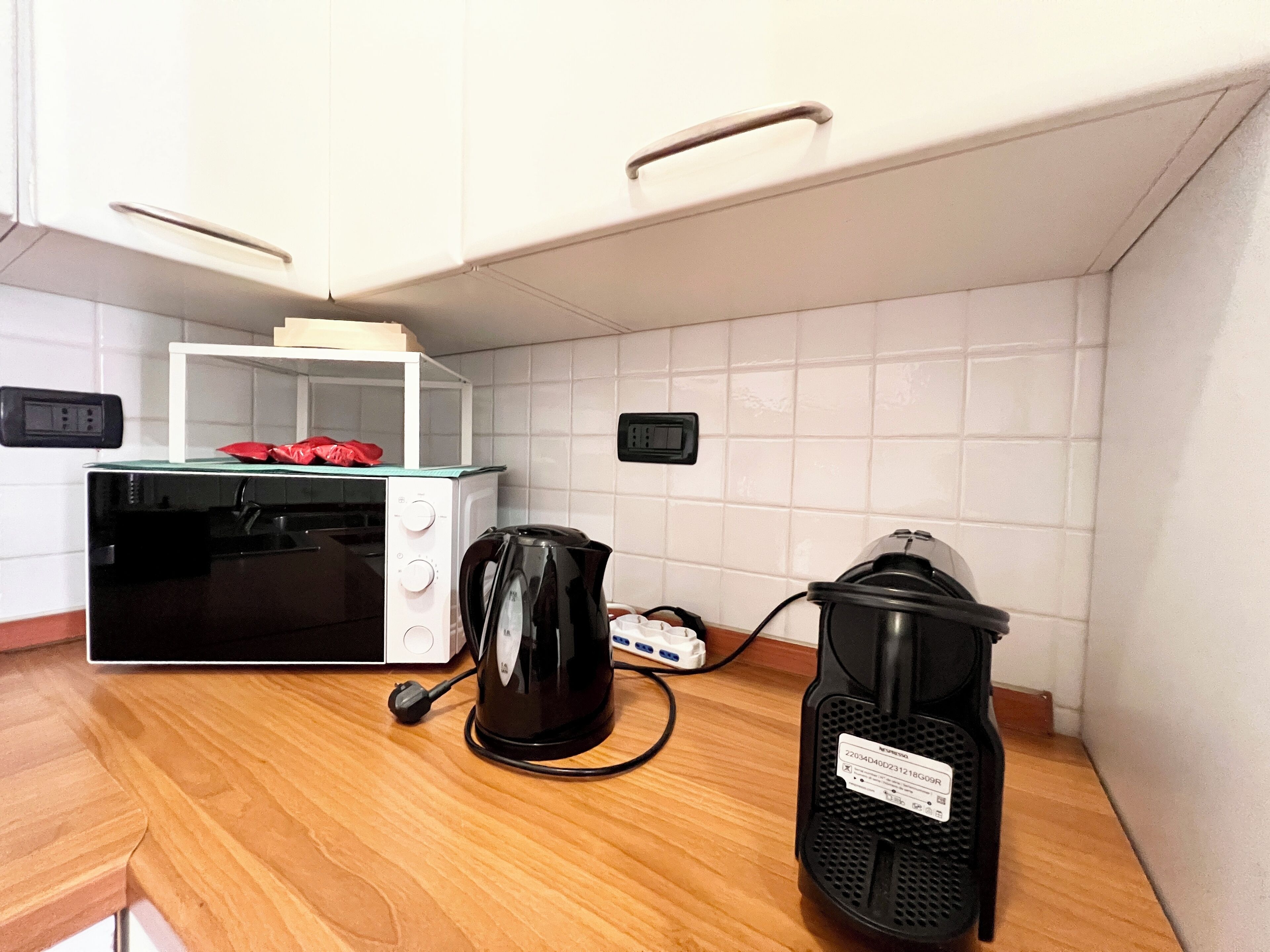 A kitchen with a microwave, toaster, coffee maker, and a portable air purifier on a wooden countertop.