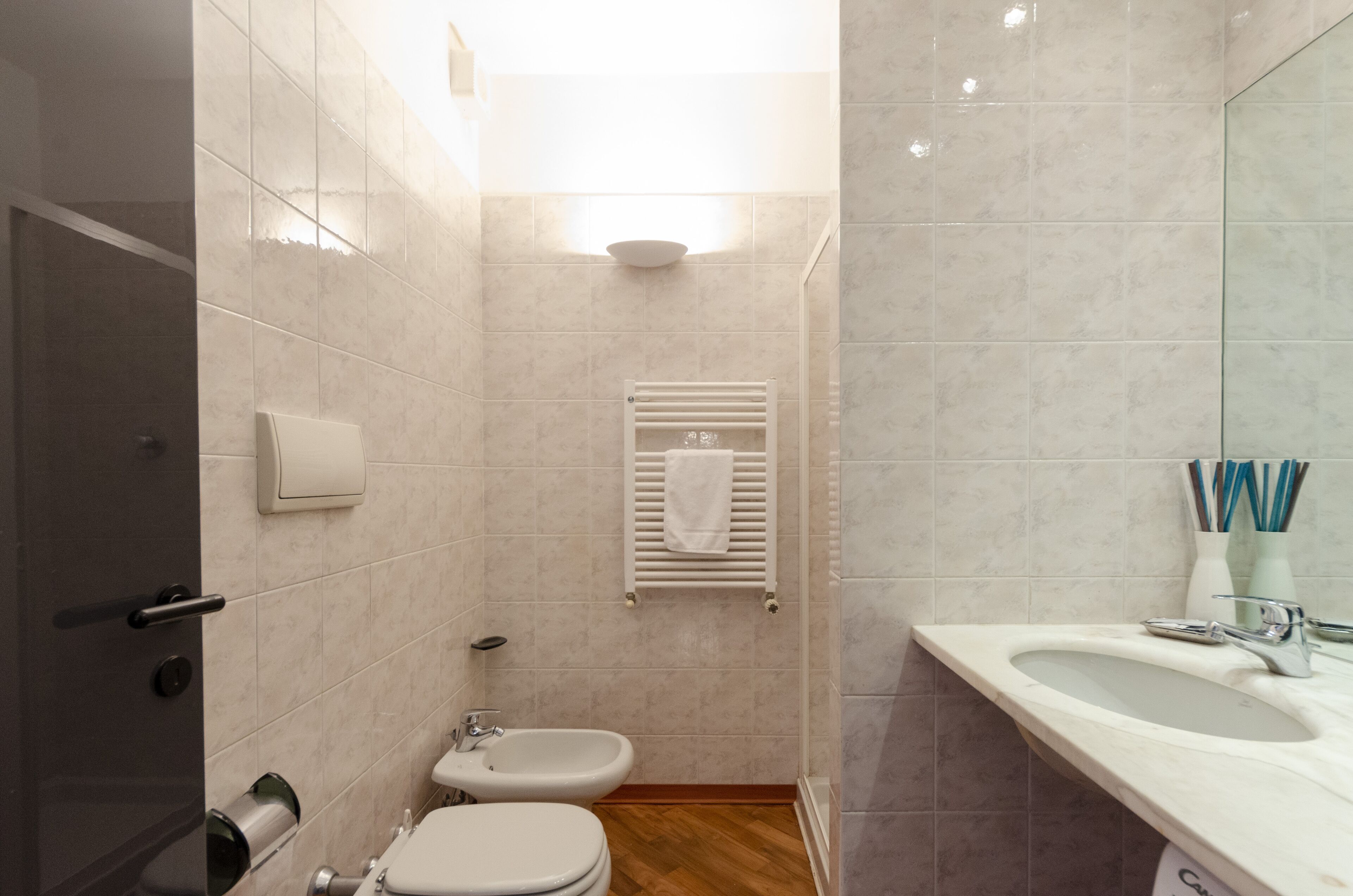 Ein modernes Badezimmer mit Toilette, Bidet, Waschbecken und Handtuchhalter.