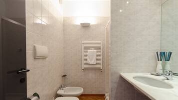 Ein modernes Badezimmer mit Toilette, Bidet, Waschbecken und Handtuchhalter.