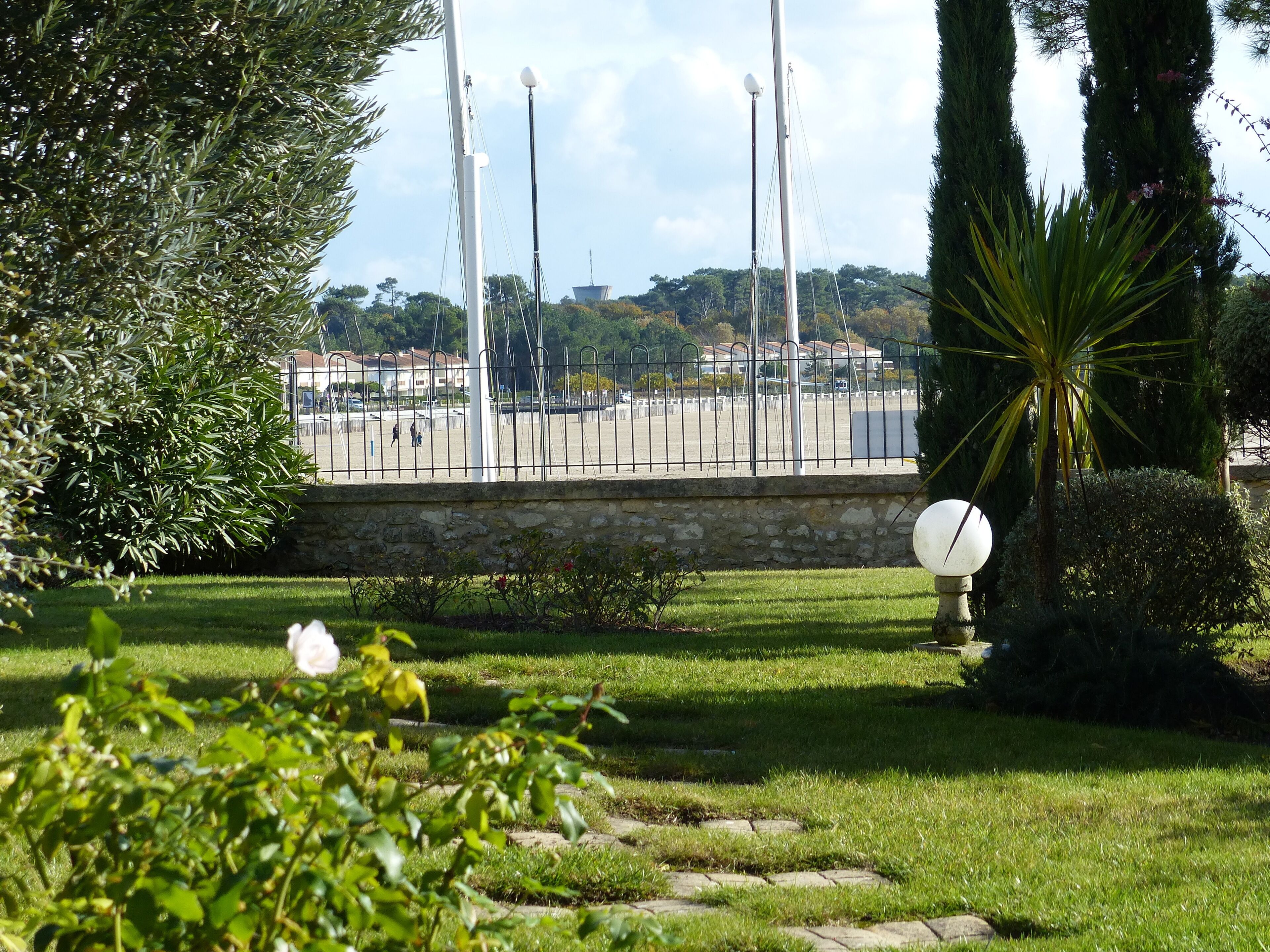Un parc avec un mur en pierre, un lampadaire et une zone herbeuse plantée.