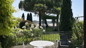Un patio con una mesa redonda y sillas, rodeado de follaje y vistas a árboles distantes.