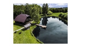 En hytte ved søen med en anløbsbro, omgivet af frodig vegetation.