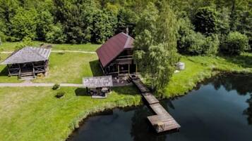 Eine Holzhütte mit rotem Dach und einem Steg, der in einen See hineinreicht, umgeben von dichtem Wald.